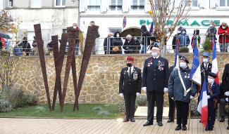 Cérémonie : Militaires et porte-drapeaux à proximité d'un œuvre d'art composé de lames en métal