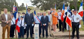 Elus, représentants de l'Etat, porte-drapeaux autour d'une borne rectangulaire blanche
