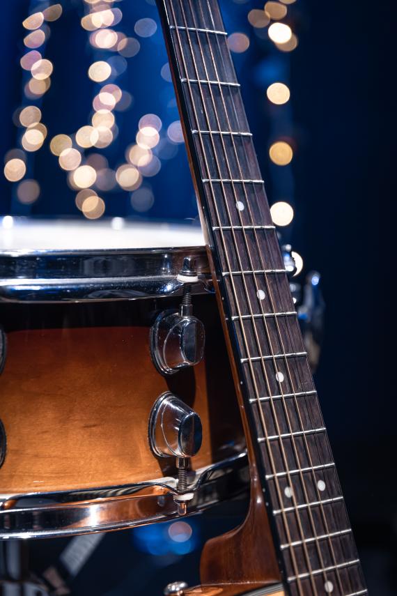 Snare drum and guitar on a blurry dark background with bokeh.